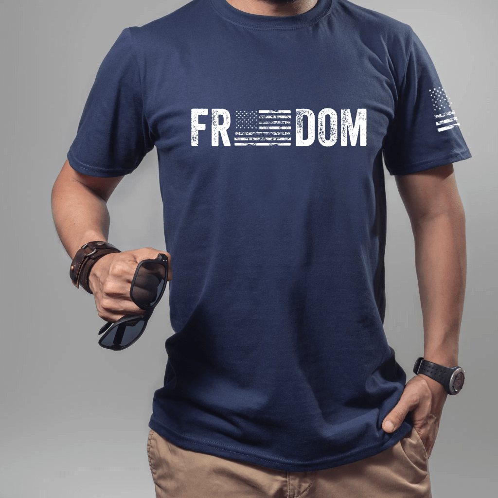 Unisex Freedom T-shirt, short sleeve navy.  "Freedom" is printed in white on the front chest with an American flag replacing the 'e's in the word.  American flag is also printed on the left sleeve.