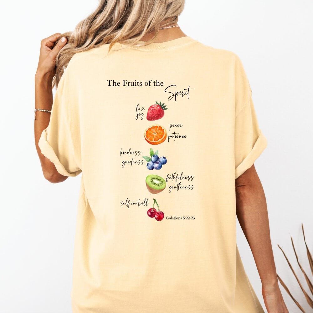 Fruits of the Spirit T-shirt short sleeve butter color. Crew neck t-shirt with Fruit design down the back listed with the Fruits of the Spirit from Galatians 5:22-23. The front has a strawberry on the top left corner chest.