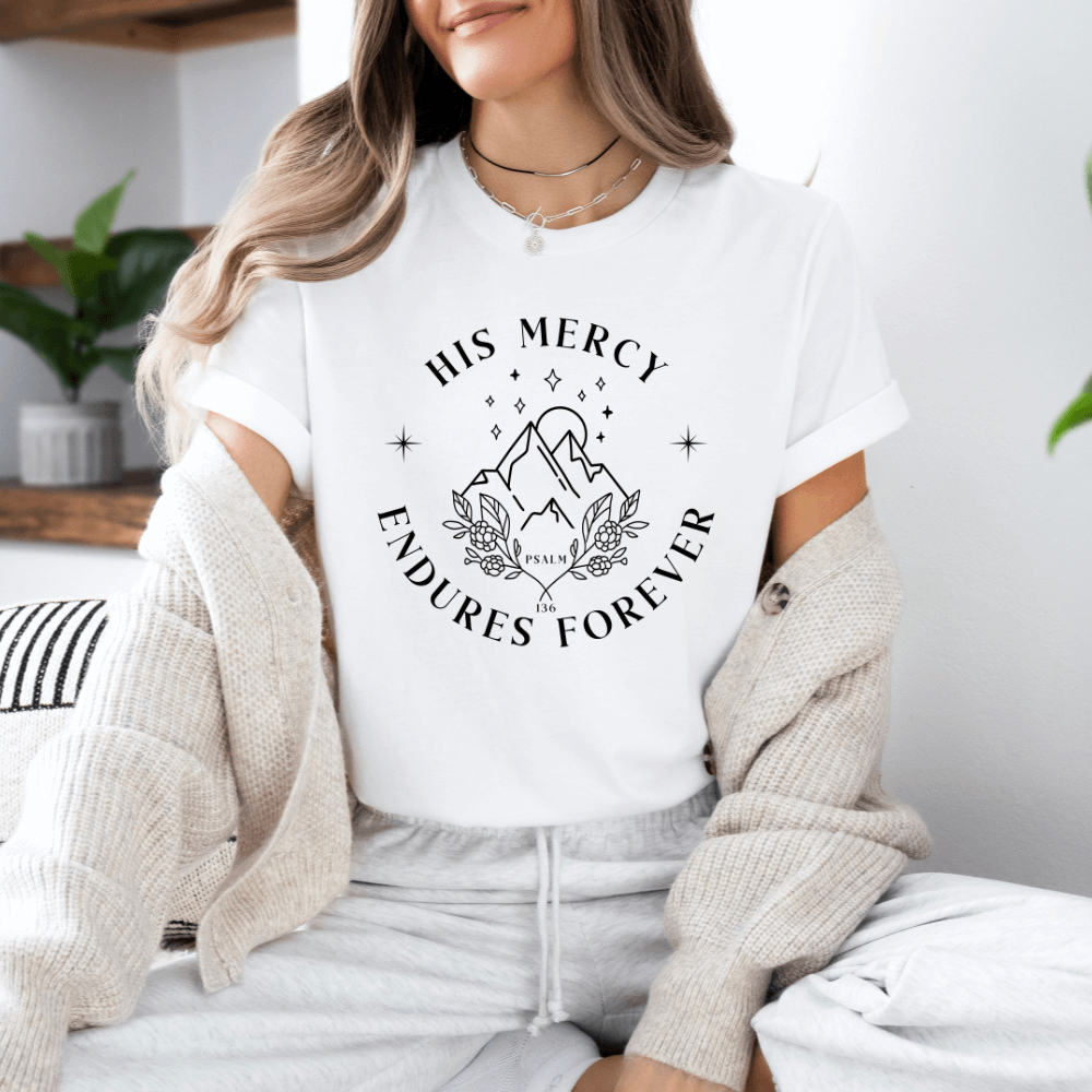His Mercy Endures forever short sleeve women's t-shirt white.  Design of mountains in black with "His Mercy Endures Forever" printed on the front around the design. "Psalm 136" printed in small font.