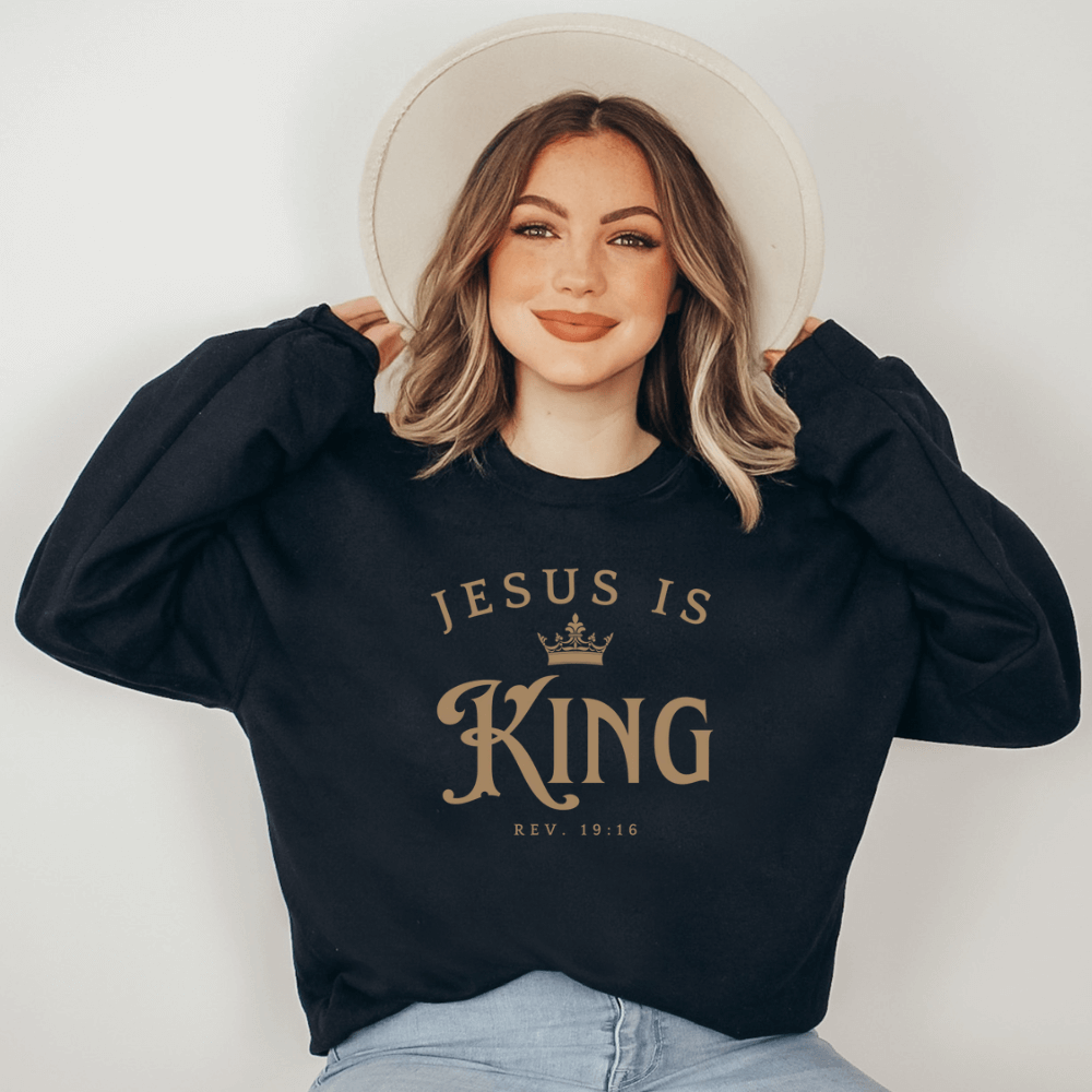 Unisex Jesus Is King Sweatshirt black. Design on front  chest in light tan with Rev. 19:16 below the design.