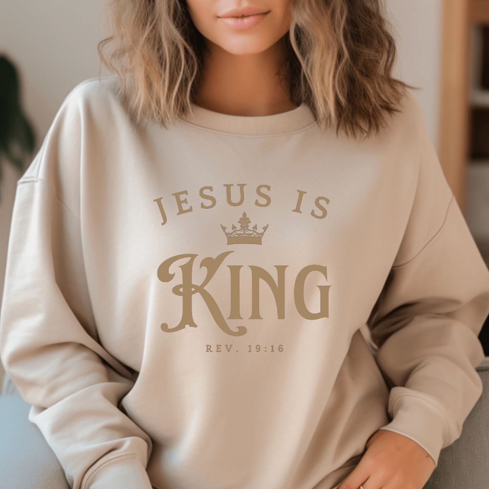 Unisex Jesus Is King Sweatshirt sand. Design on front  chest in light tan with Rev. 19:16 below the design.