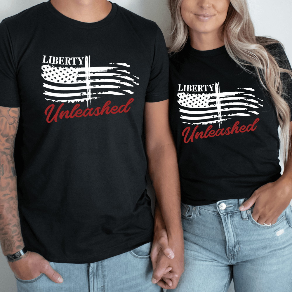 Liberty Unleashed Unisex T-shirt short sleeve black.  White American flag on the front chest with a cross in the middle and "Liberty Unleashed" printed above and below the flag.