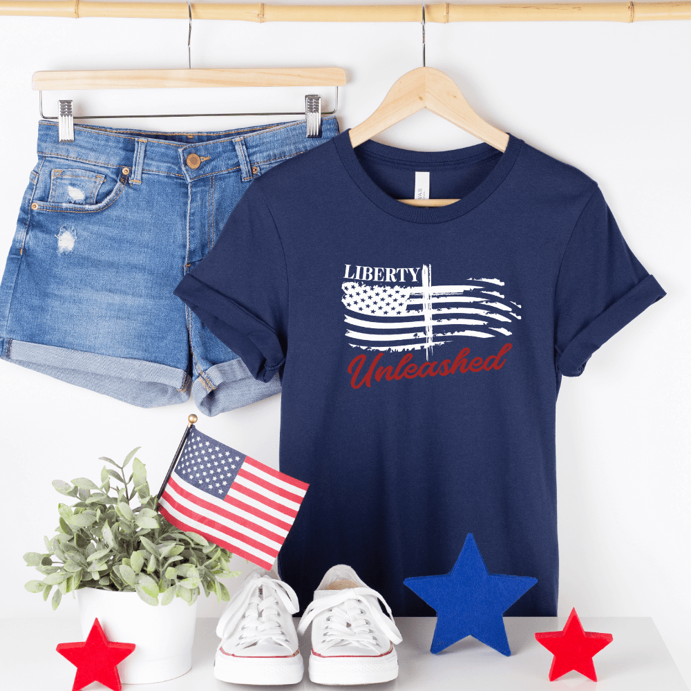 Liberty Unleashed Unisex T-shirt short sleeve navy.  White American flag on the front chest with a cross in the middle and "Liberty Unleashed" printed above and below the flag.