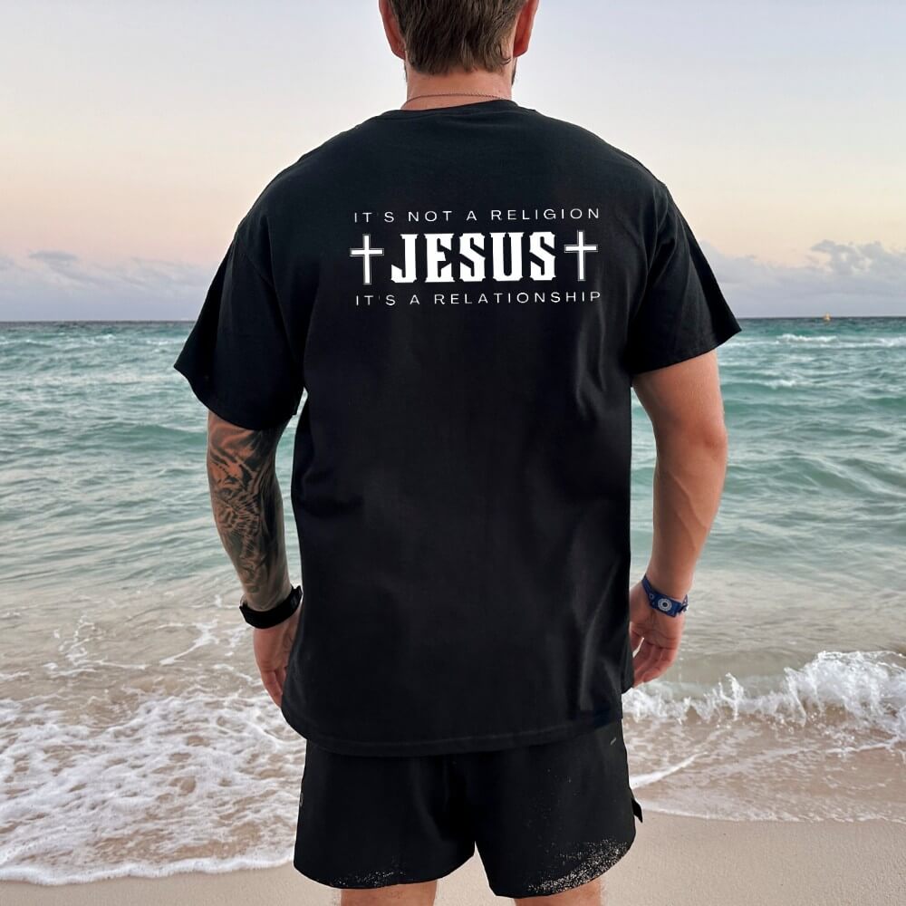Not a Religion mens shirt black short sleeve. The back has a design printed in white that says " JESUS" in large capital letters. Above says" It's not a religion" below "Jesus" says "It's a relationship.