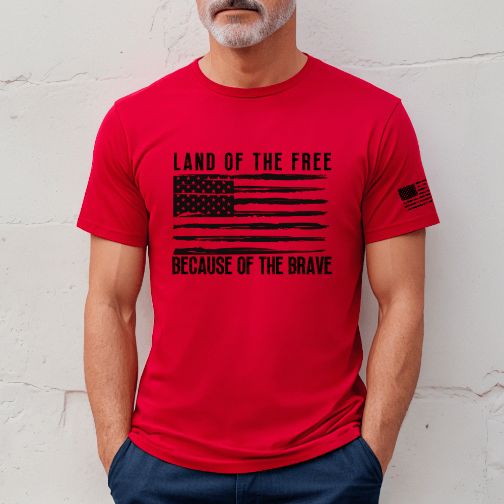 Land of the Free t-shirt, short sleeve red. American flag printed in black on front chest with 'Land of the Free, Because of the Brave" written above and below the flag.  American flag is also printed on the left sleeve.