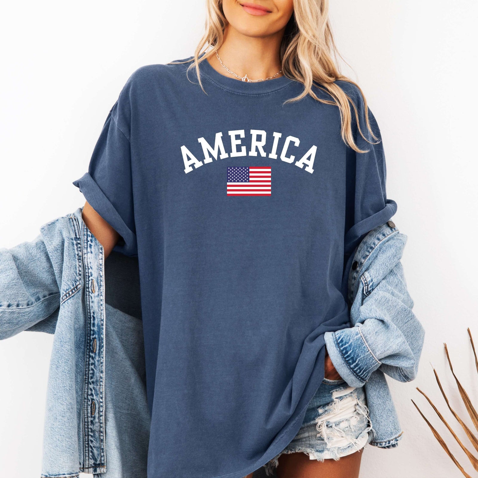 America T-shirt denim color. Short sleeve unisex t-shirt with American flag and "America" printed above it in white