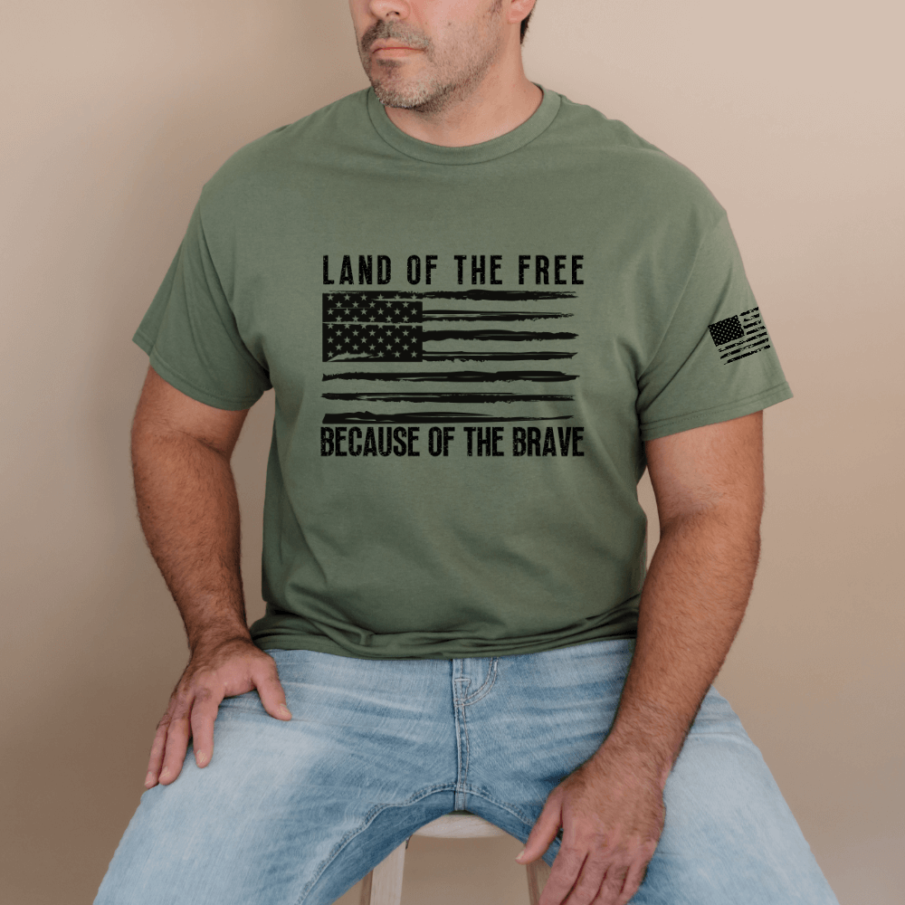 Land of the Free t-shirt, short sleeve military green. American flag printed in black on front chest with 'Land of the Free, Because of the Brave" written above and below the flag.  American flag is also printed on the left sleeve. 
