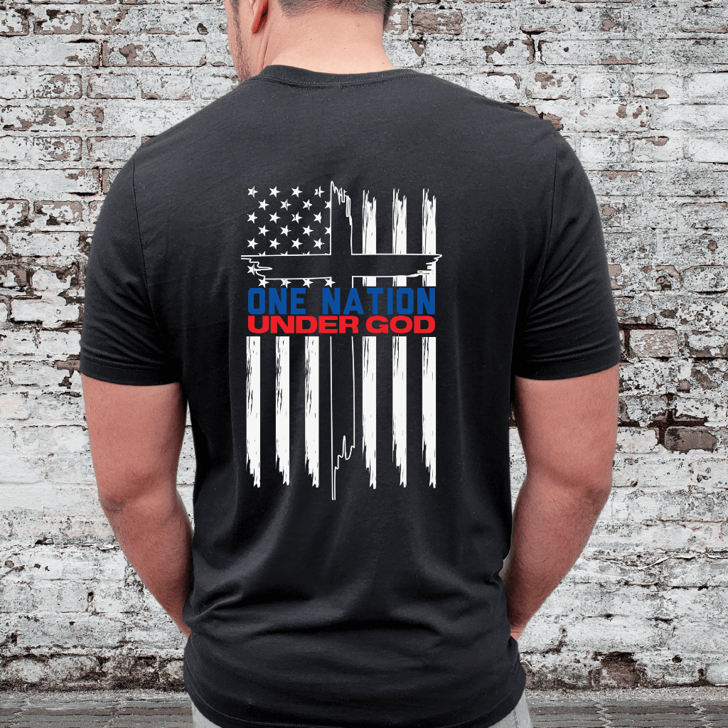 Unisex One Nation Under God T-shirt black.  White American flag printed on the back with a large cross in the middle. Under the Cross is printed "One Nation Under God" in red and blue.