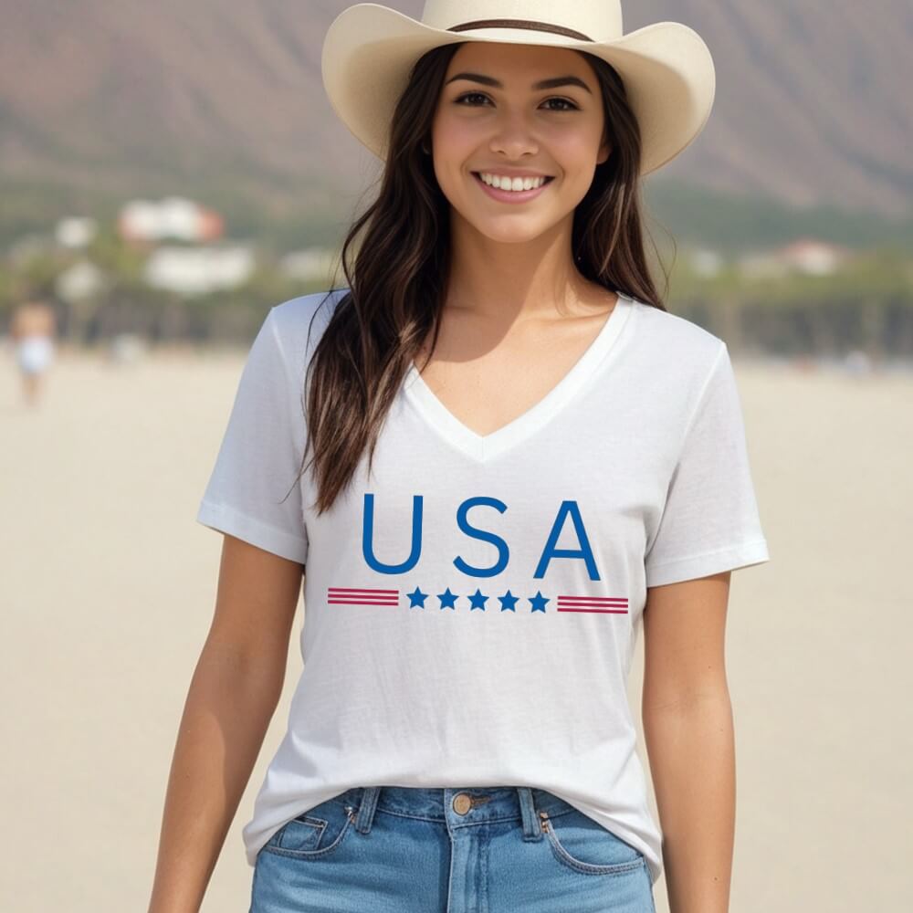 USA Women's V-neck t-shirt.  White short sleeve women's v-neck shirt with "USA" printed on the front chest in blue with red strips and blue stars underneath. 