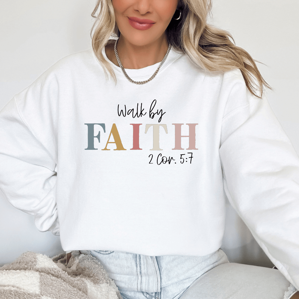 Walk By Faith crewneck sweatshirt white. On the front chest is printed "Walk by FAITH 2 Cor. 5:7" in multicolored pastel letters. 