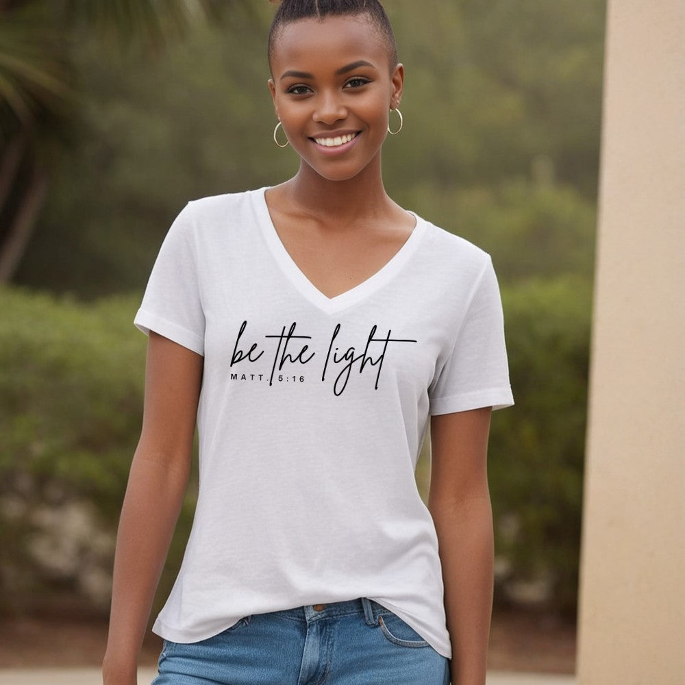 Be The Light women&#39;s V-neck t-shirt white short sleeve.   &quot;be the light - Matt. 5:16&quot; printed in black on front chest. 